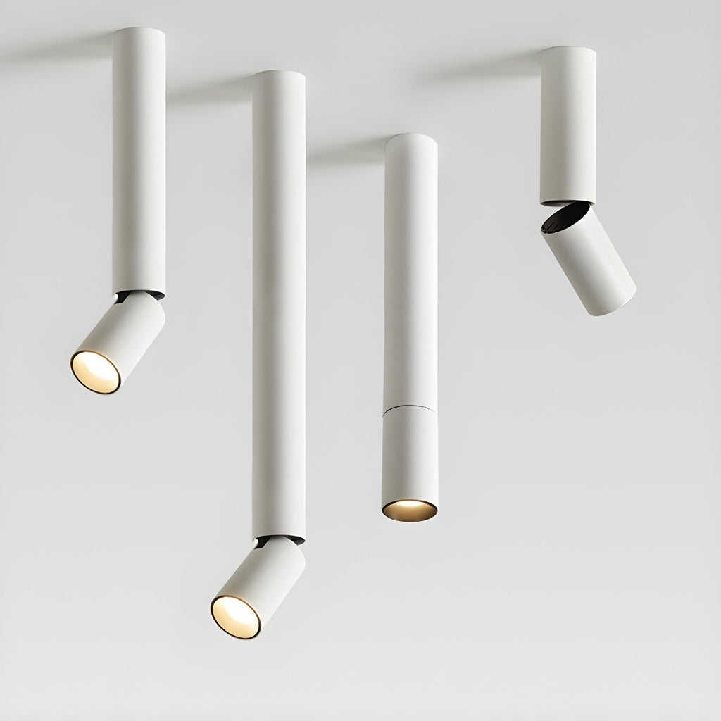 Four white Clérachic spotlights in different pole lengths on a pale backdrop, three with angled heads and one with a straight head.