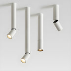 Four white Clérachic spotlights in different pole lengths on a pale backdrop, three with angled heads and one with a straight head.