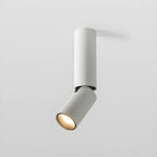 This white Clérachic spotlight has a medium pole and a tilted head, with a warm glow in its recessed lens.