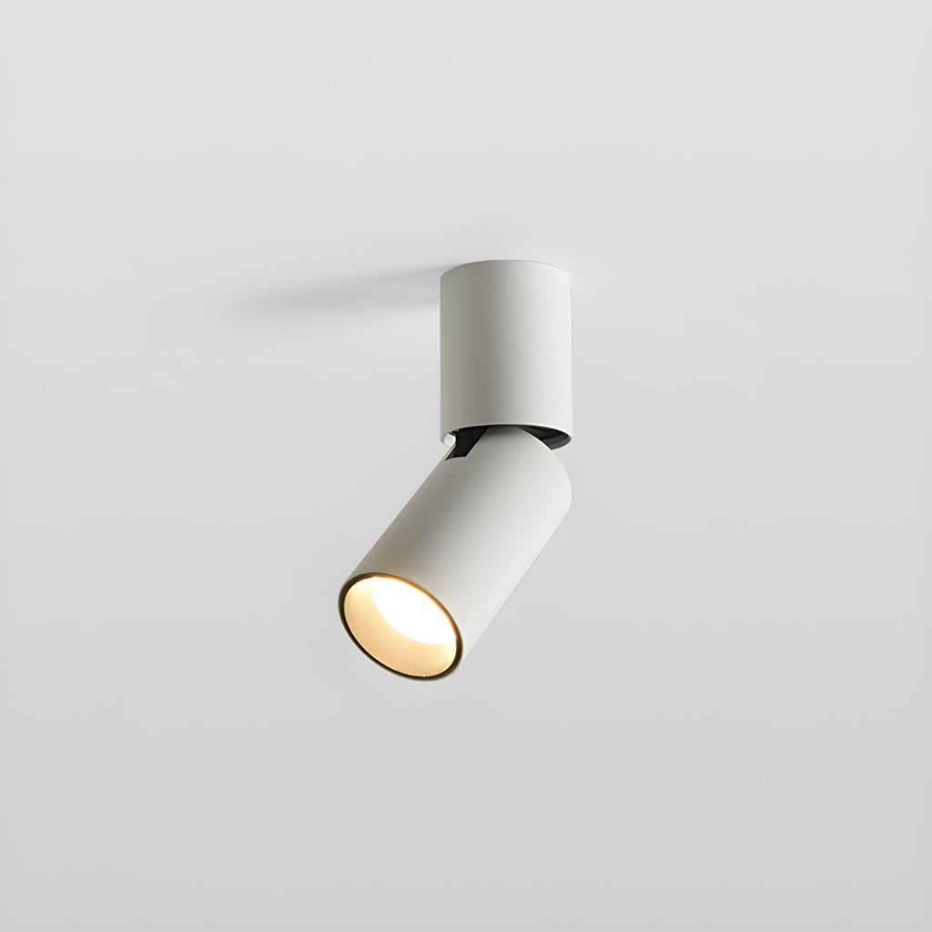A short white Clérachic spotlight with its head turned to one side, the lens glowing warm, on a light grey backdrop.