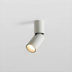A short white Clérachic spotlight with its head turned to one side, the lens glowing warm, on a light grey backdrop.