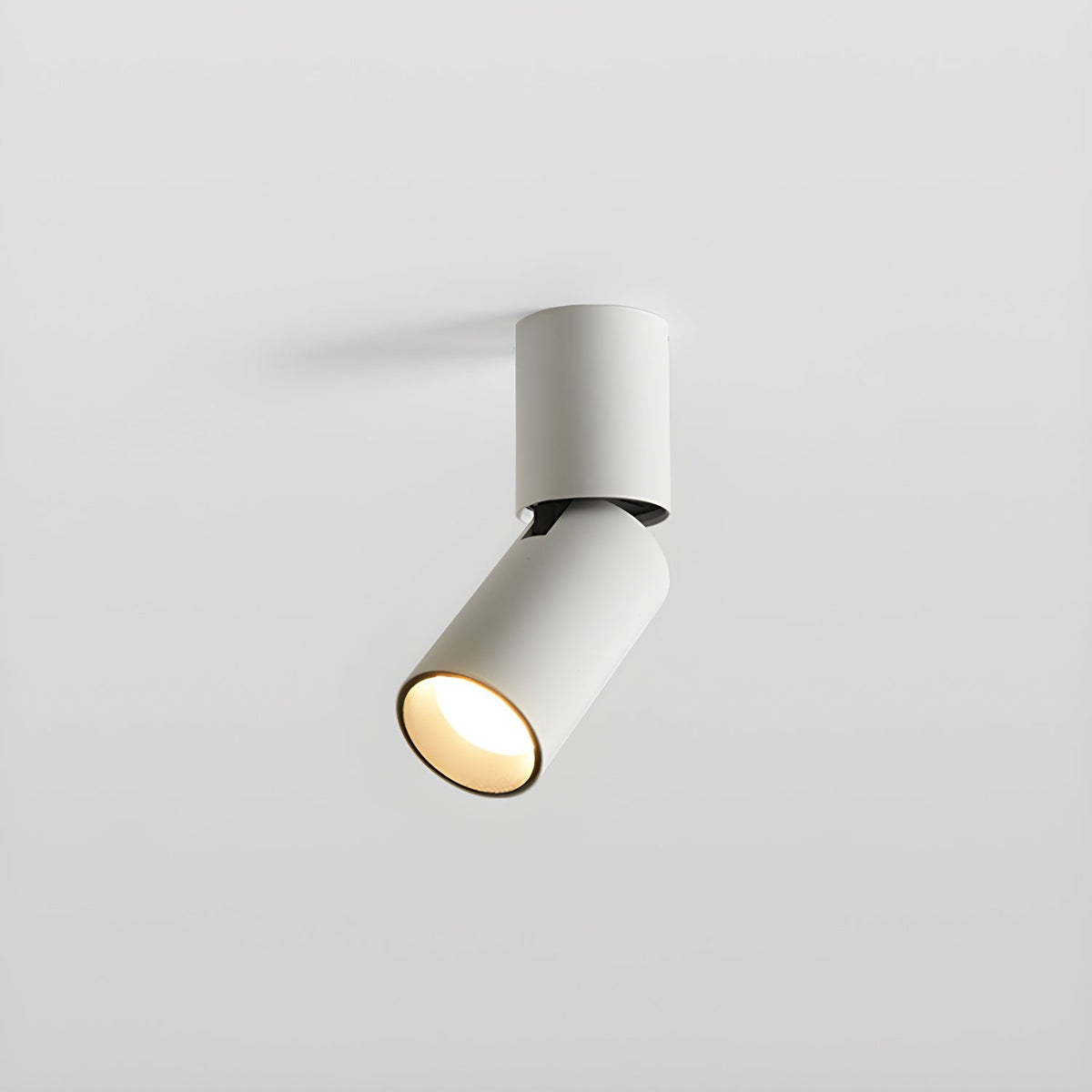 A short white Clérachic spotlight with its head turned to one side, the lens glowing warm, on a light grey backdrop.
