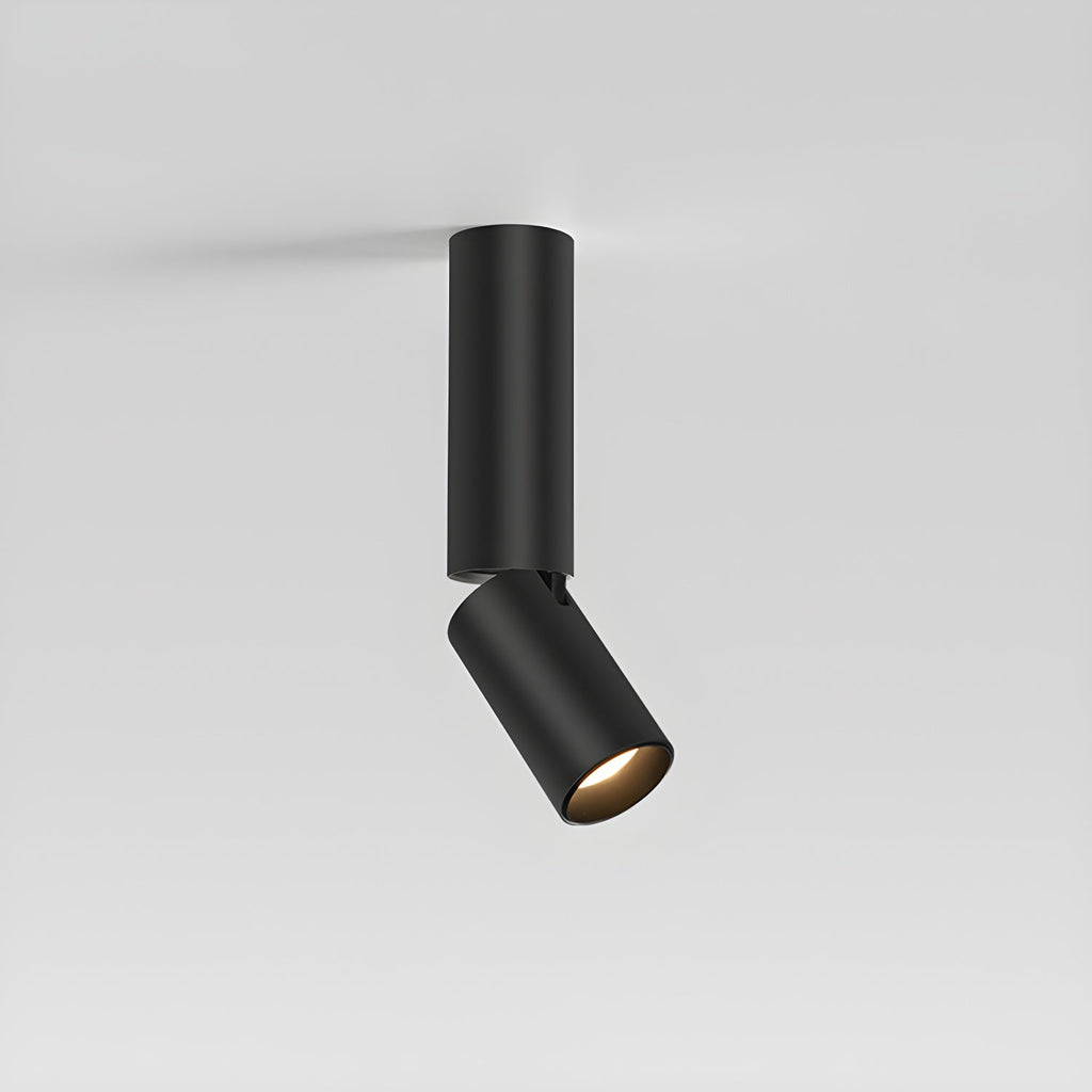 Medium-length black Clérachic spotlight with its head tilted at an angle, seen against a pale grey wall.