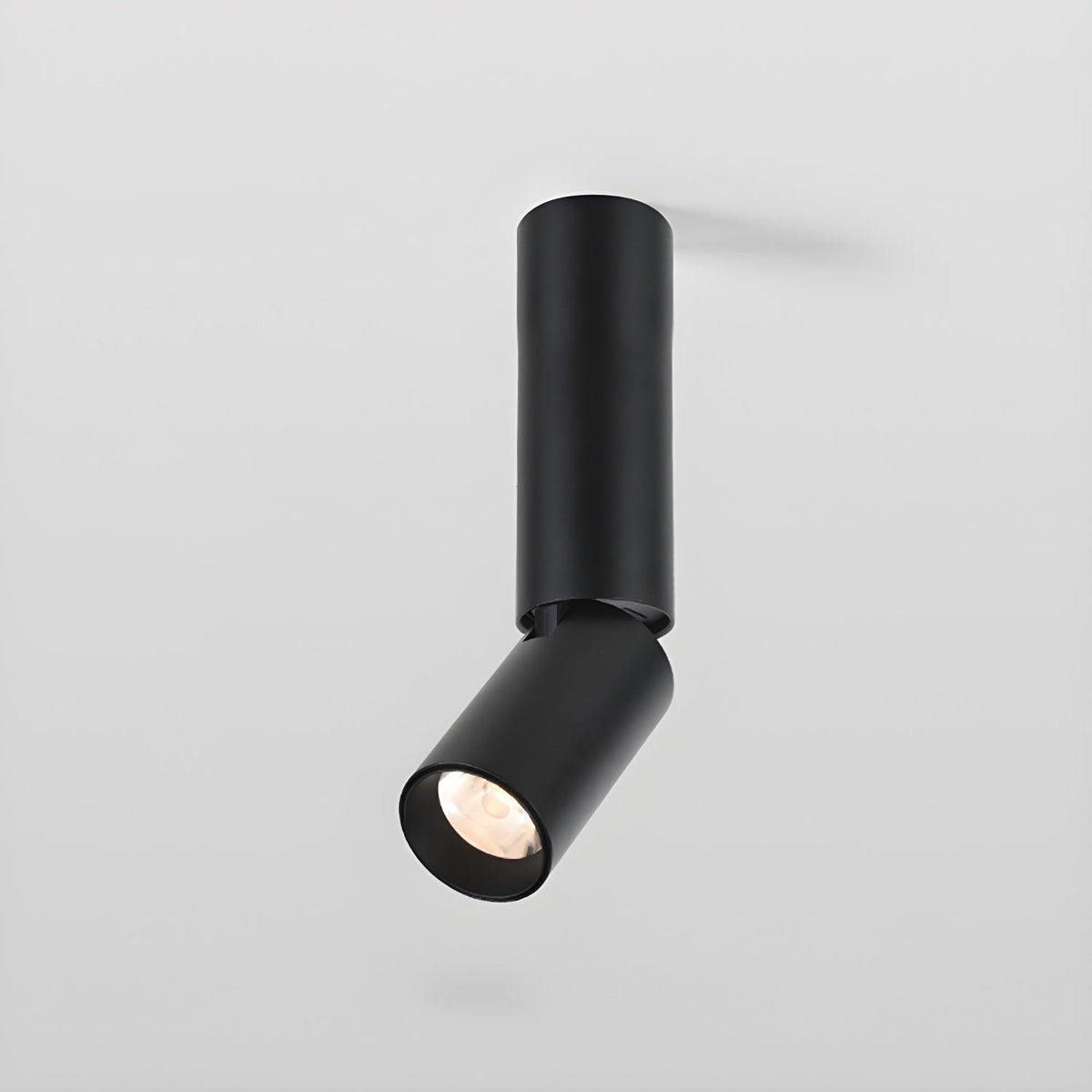 A black Clérachic spotlight with a longer pole and a tilted head, its lens showing a faceted reflector.