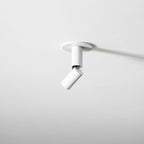 White Clérachic spotlight on a white ceiling, its slim head swung away at an angle, casting a soft shadow.