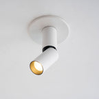 Close view of this white Clérachic spotlight in its round ceiling plate, a black ring at the joint and a warm gold-toned lens.