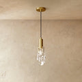 A Clérachic brass pendant holds a rough-cut clear crystal glass shade in a brass bracket against plastered walls.