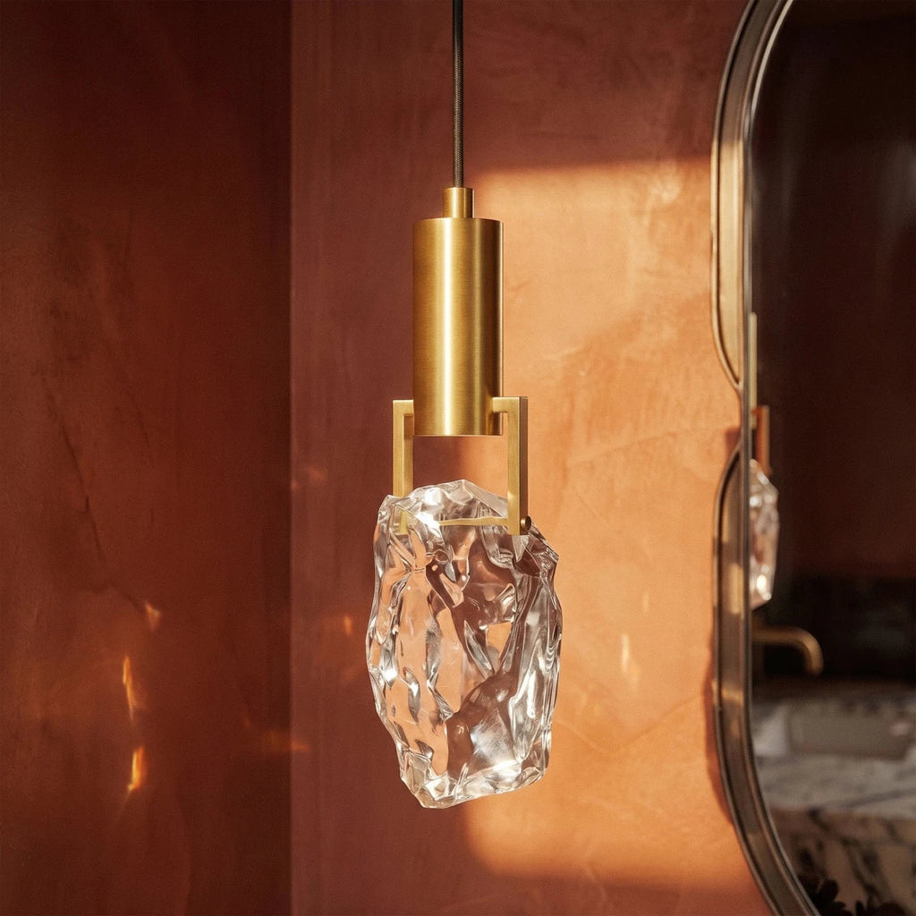 Close-up on the Clérachic pendant's faceted crystal glass and brass bracket, warm light catching every angled cut.