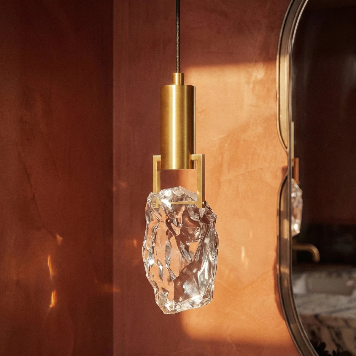 Close-up on the Clérachic pendant's faceted crystal glass and brass bracket, warm light catching every angled cut.