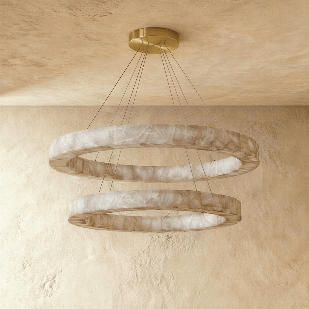 Clérachic alabaster chandelier with two glowing rings, hung on slim cords against a plaster ceiling and wall.