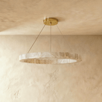 Clérachic alabaster ring chandelier glowing warm, its veined stone band hung low on slender ceiling cords.