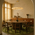 Clérachic single-ring alabaster chandelier glowing above a round dining table set on a green rug.