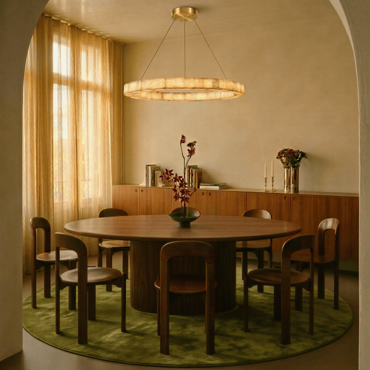 Clérachic single-ring alabaster chandelier glowing above a round dining table set on a green rug.