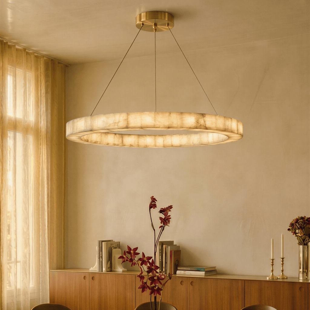 Clérachic two-tier alabaster chandelier glowing above a sideboard styled with books, candlesticks and flowers.