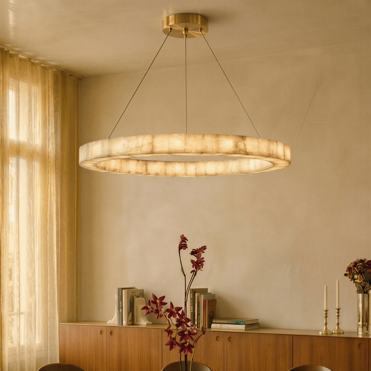 Clérachic two-tier alabaster chandelier glowing above a sideboard styled with books, candlesticks and flowers.