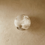 Clérachic alabaster wall lamp switched off, its rounded stone dome showing soft grey and cream veining on a plaster wall.