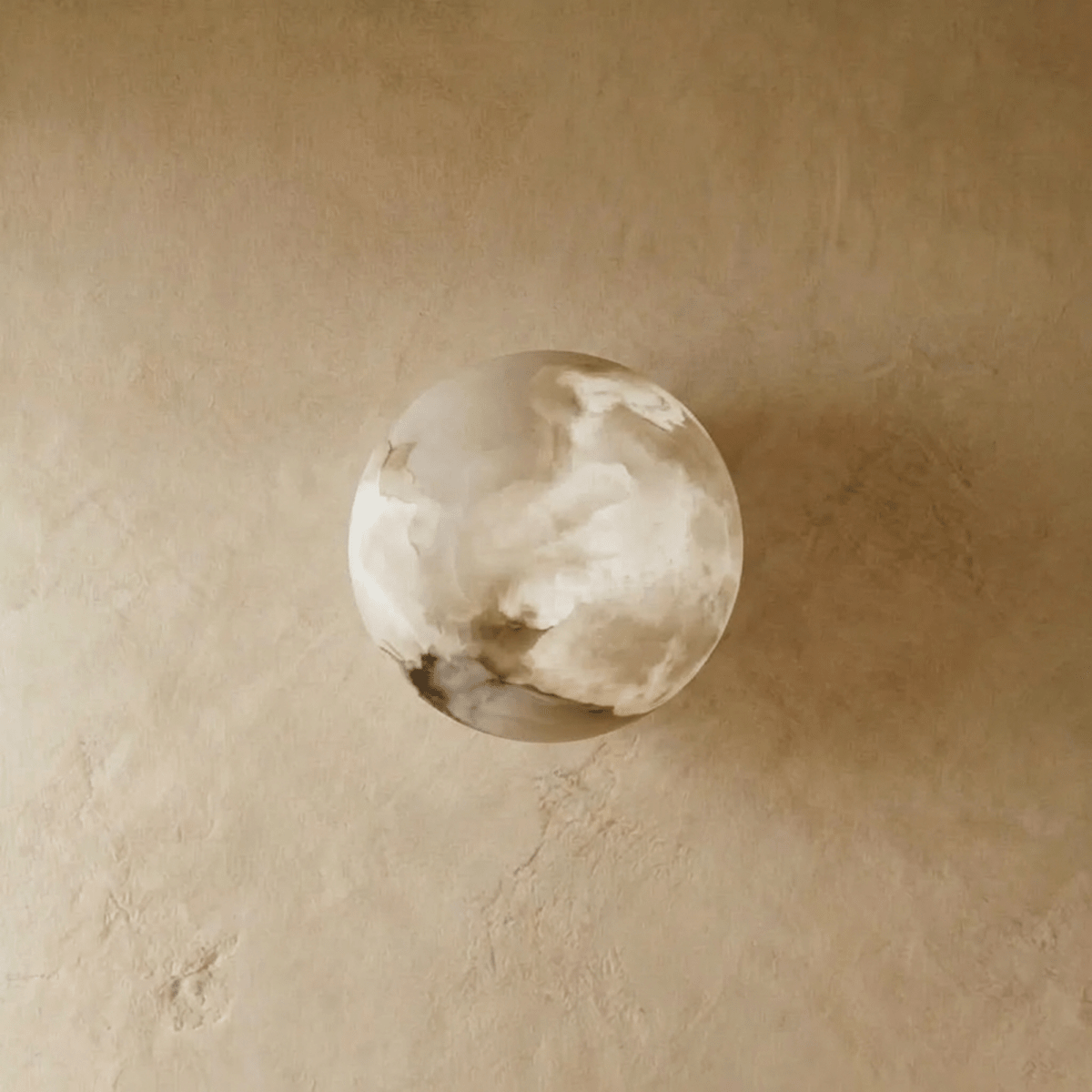 Clérachic alabaster wall lamp switched off, its rounded stone dome showing soft grey and cream veining on a plaster wall.