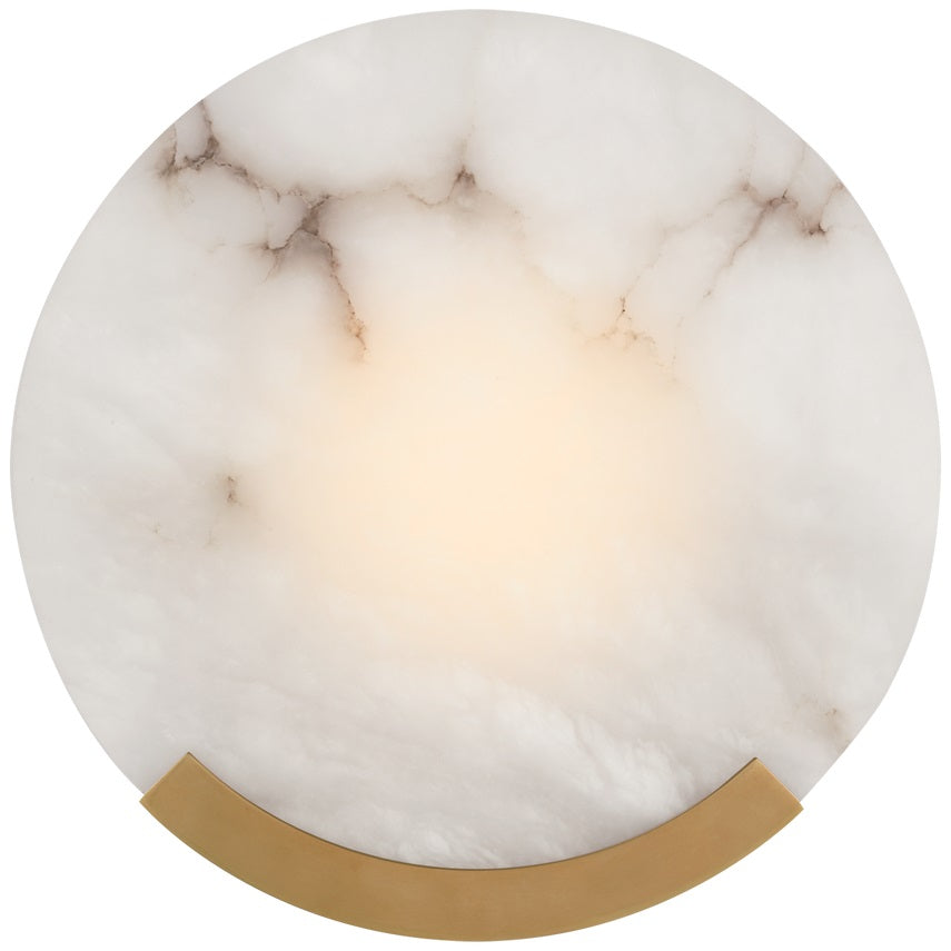 Brass-bracket version of the Clérachic alabaster wall sconce, lit so the veining reads as a warm halo at the centre.
