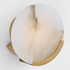 Clérachic round wall sconce seen at an angle, the brass bracket and round back plate visible behind the lit disc.