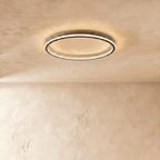 The Clérachic round ceiling light glows in matte black against a softly textured plaster ceiling and wall.