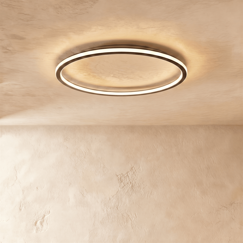Close angle on the Clérachic matte black ceiling ring, showing the slim frame and warm glow along its rim.