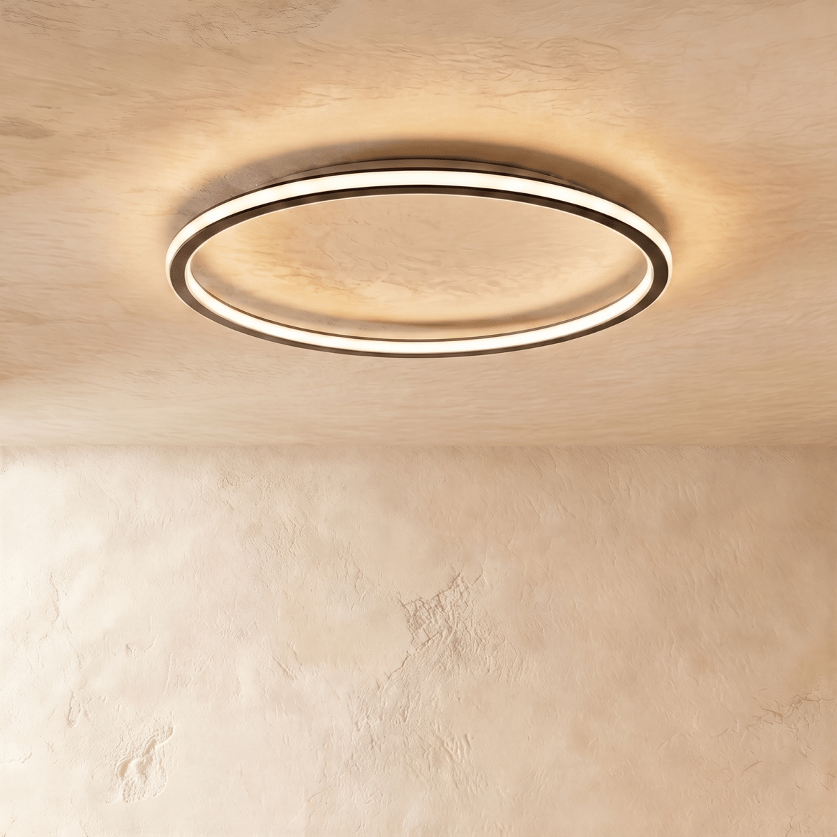 The Clérachic round ceiling light in matte black, lit warm white, mounted flush on a plain plaster ceiling.