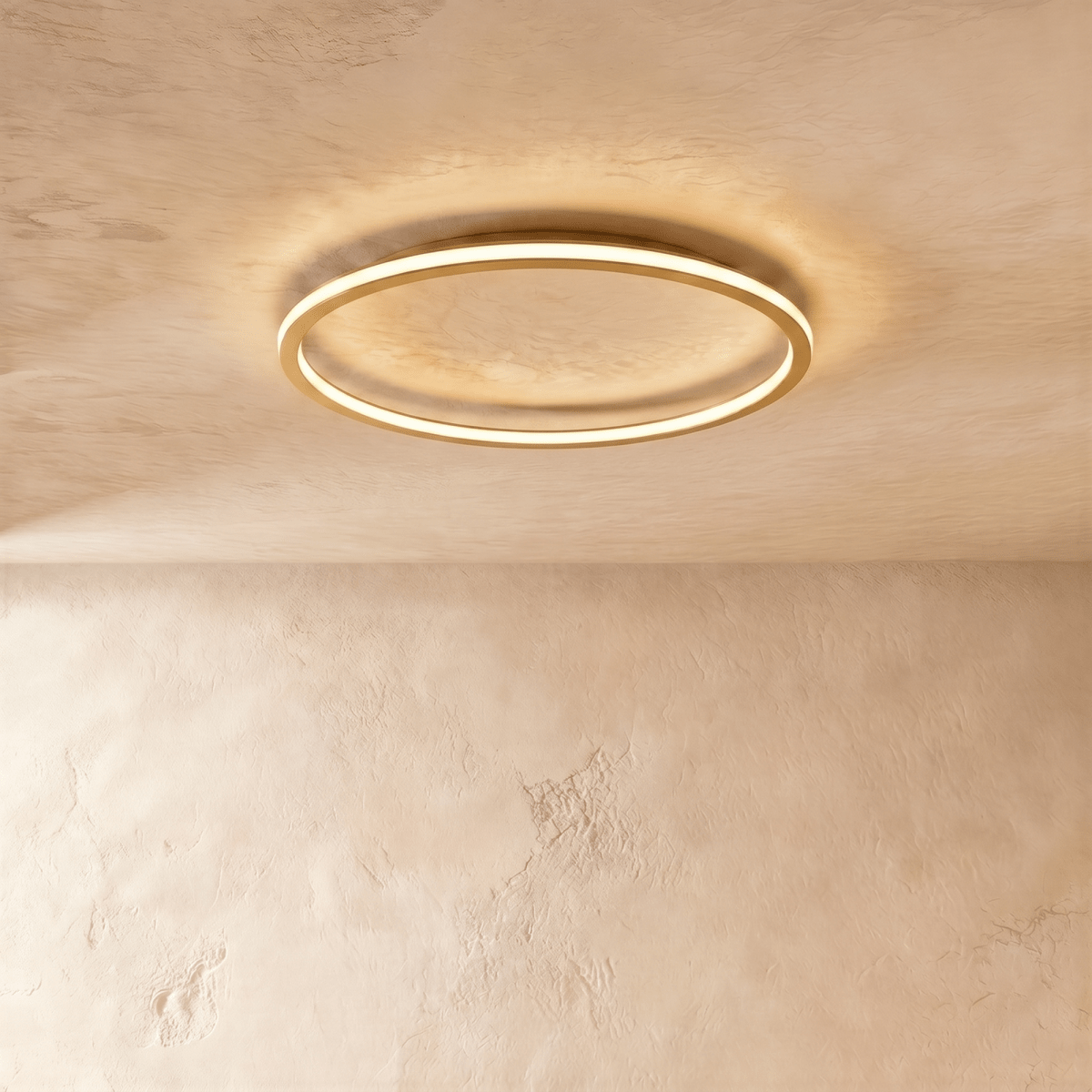 The Clérachic ceiling ring in a gold finish, its slim metal frame glowing warm white against a plaster ceiling.