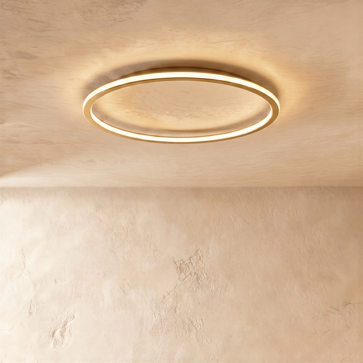 A side angle of the Clérachic gold-finish ceiling ring, its slim profile lit warm white against plaster.