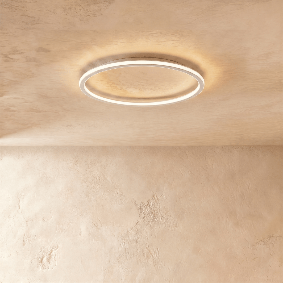 The Clérachic ceiling ring in a white finish, its slim frame glowing warm white against a plaster ceiling.
