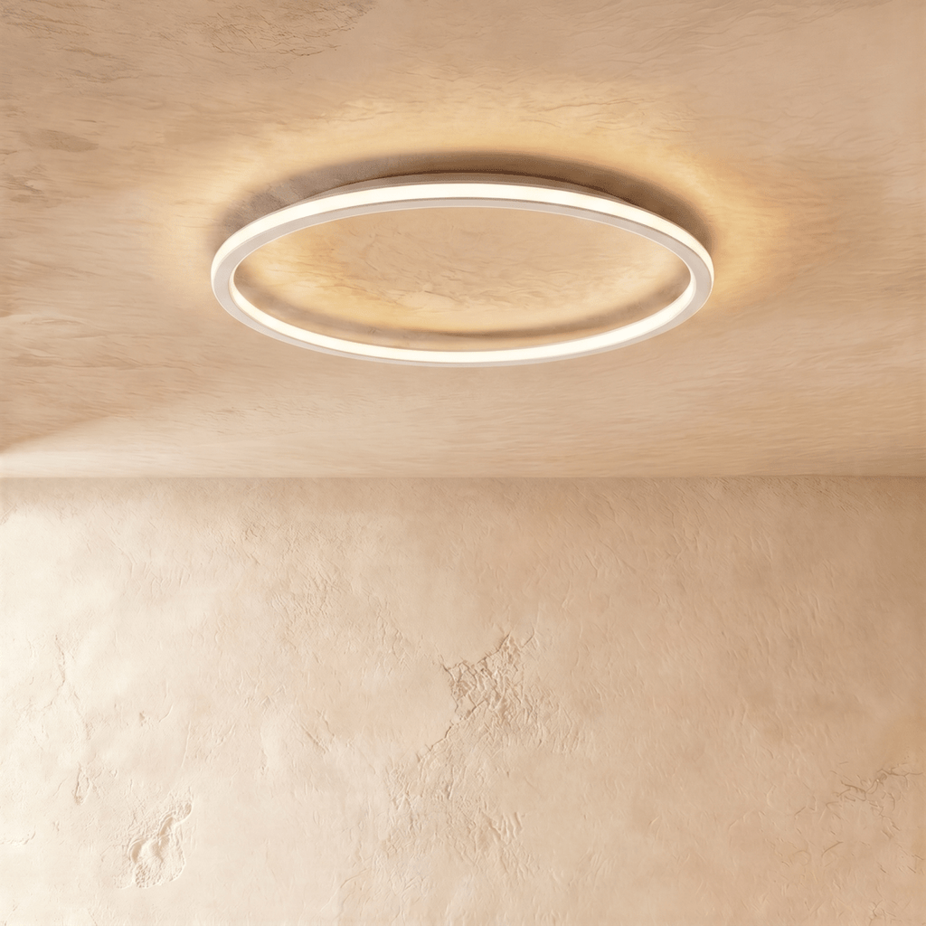 Close view of the Clérachic white ceiling ring, its slim frame lit warm white against a plaster ceiling.
