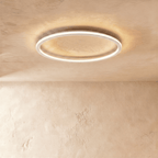Close view of the Clérachic white ceiling ring, its slim frame lit warm white against a plaster ceiling.