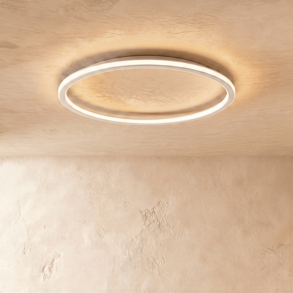 The Clérachic white ceiling ring seen from below, its slim band glowing warm white on a plain ceiling.