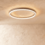 The Clérachic white ceiling ring seen from below, its slim band glowing warm white on a plain ceiling.