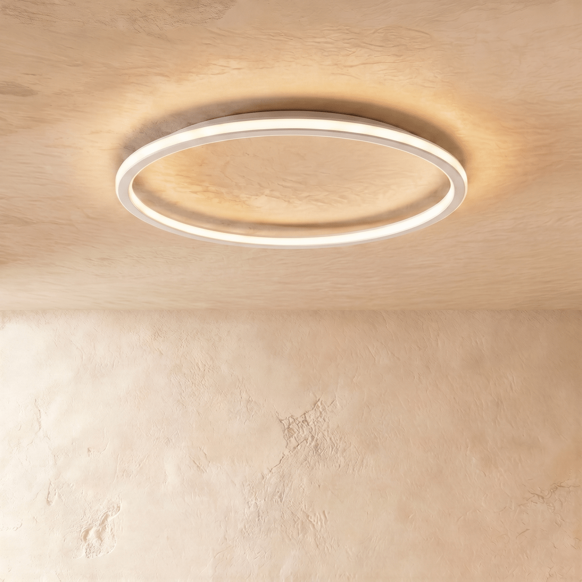 The Clérachic white ceiling ring seen from below, its slim band glowing warm white on a plain ceiling.