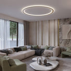 The Clérachic ceiling ring in a gold finish lights a living room with a sectional sofa and marble coffee tables.