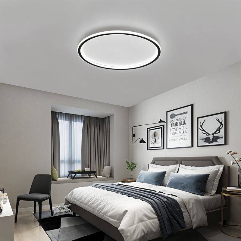 The Clérachic round ceiling light in matte black lights a bedroom with framed art above a upholstered headboard.