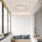 The Clérachic matte black ceiling ring lights a window nook with a cushioned bench seat and potted plants.