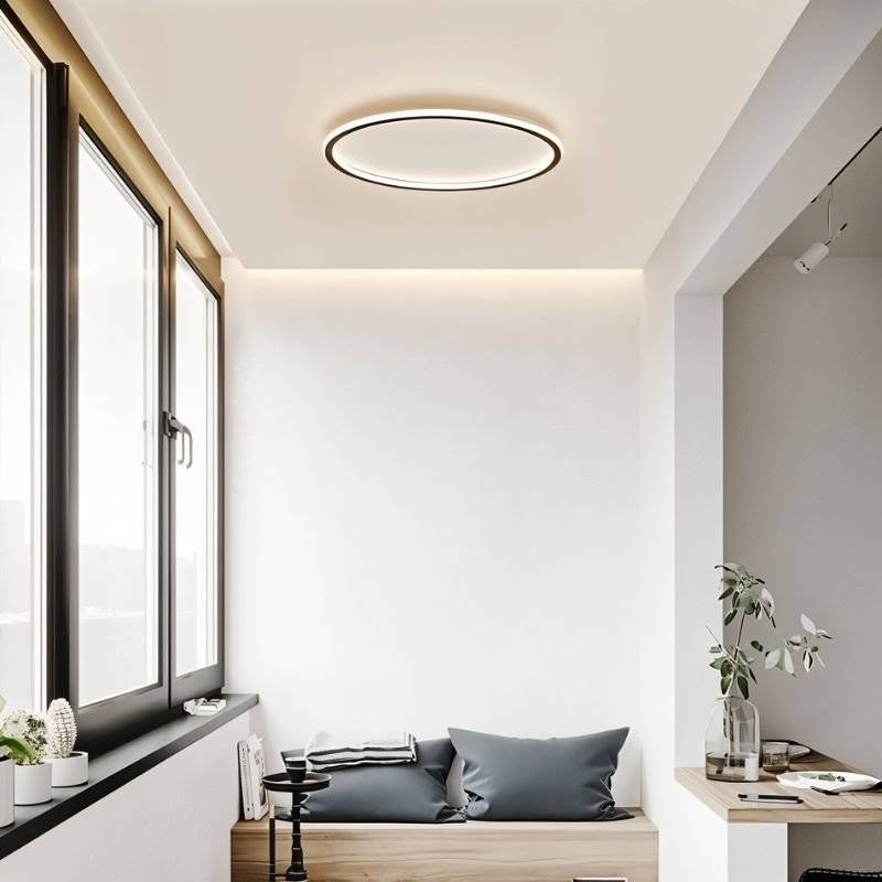 The Clérachic matte black ceiling ring lights a window nook with a cushioned bench seat and potted plants.
