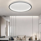 The Clérachic round ceiling light in matte black glows above a bed set against a paneled wall with a mirror.