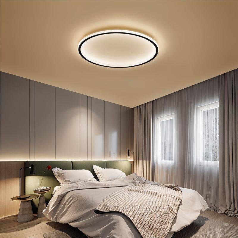The Clérachic round ceiling light in matte black glows above a bed with a green upholstered headboard.