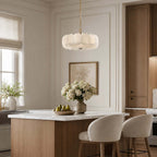 Over a kitchen island with a bowl of pears and a vase of white flowers, this Clérachic chandelier hangs in front of a framed floral print.