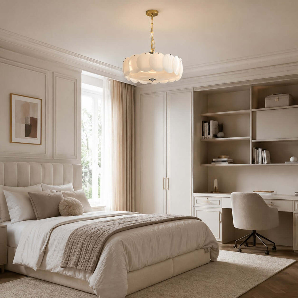 Above a bed and built-in desk, a Clérachic chandelier with a brass stem hangs in a cream room with open shelving and a wardrobe.