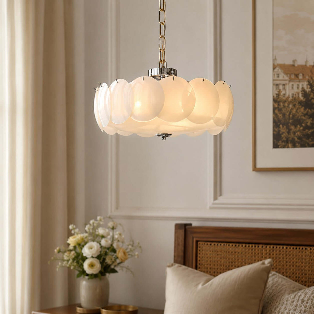Close on a Clérachic chandelier with a chrome canopy, its glowing white glass discs fixed by small black pins, with flowers in the background.
