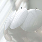 Close view of the frosted white glass discs on this Clérachic chandelier, their black retaining pins and soft ribbed texture in focus.