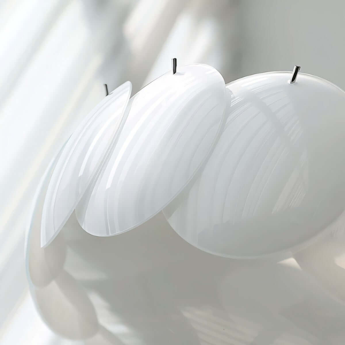 Close view of the frosted white glass discs on this Clérachic chandelier, their black retaining pins and soft ribbed texture in focus.