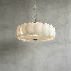 Underside view of the largest chrome Clérachic chandelier, its white discs ringed round a lit glass base on a grey plaster wall.
