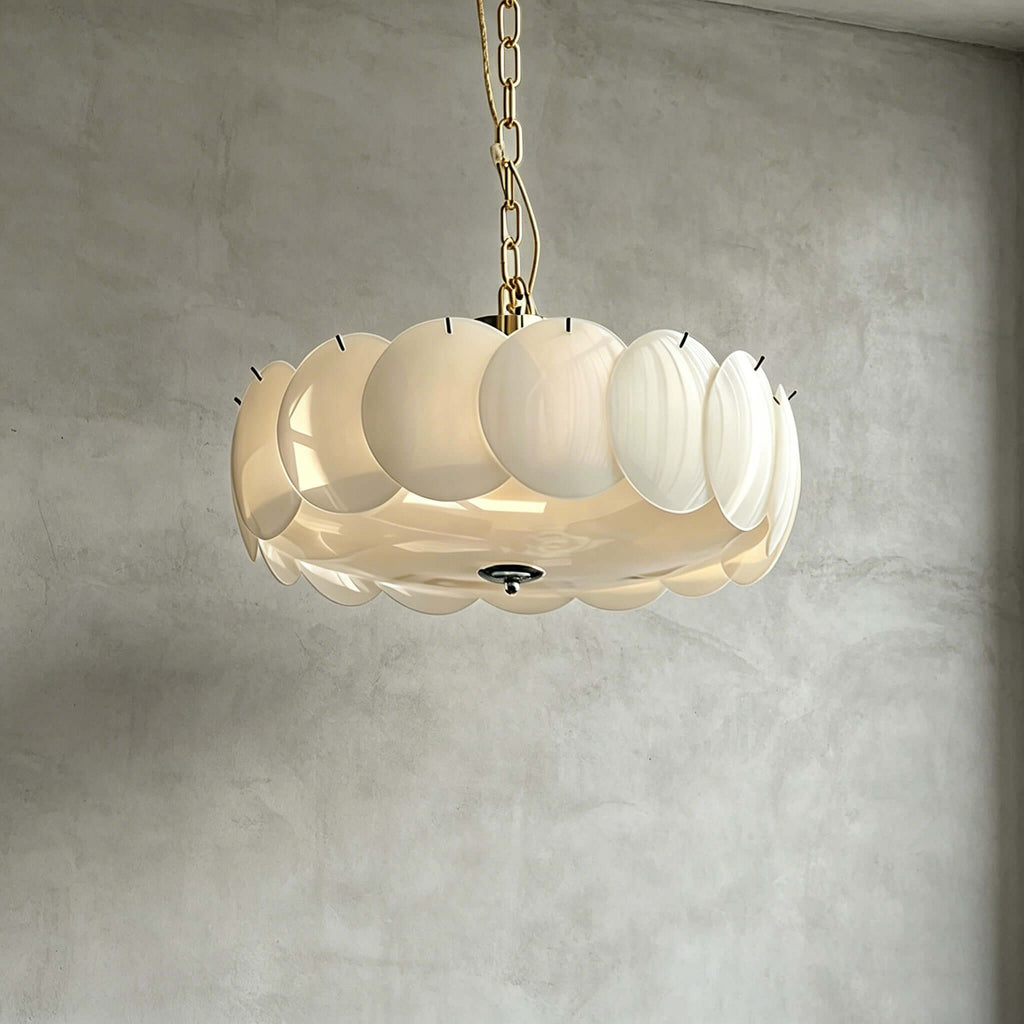 Underside view of the largest brass Clérachic chandelier, its white glass discs ringed round a lit base on a grey plaster wall.
