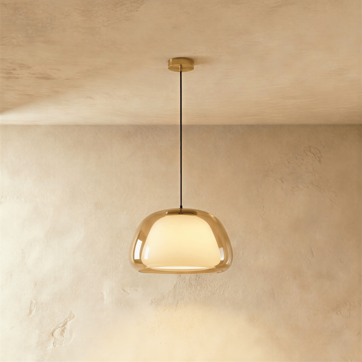 Clérachic pendant light with an amber-tinted glass outer shade around a glowing opal diffuser, hung from a brass canopy.