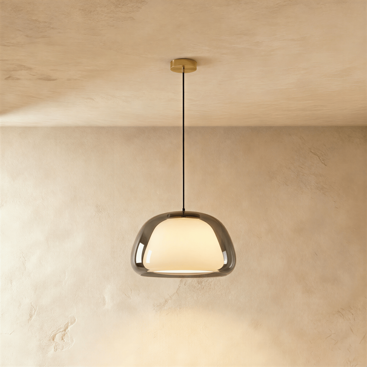 Clérachic pendant light with a smoked grey glass outer shade around a glowing opal diffuser on a black cord and brass canopy.
