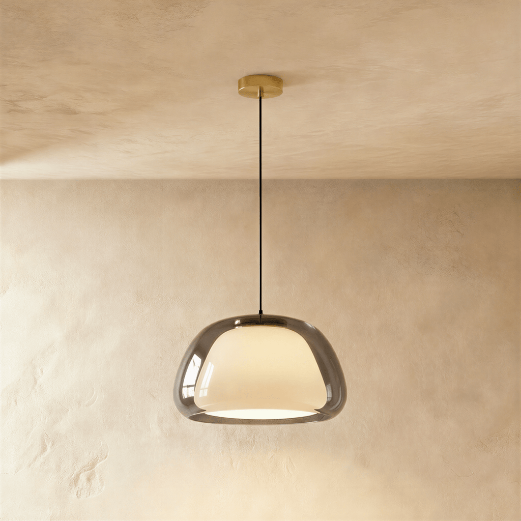 Clérachic larger pendant light in smoked grey glass over a glowing opal inner shade, brass canopy and cord against limewash.